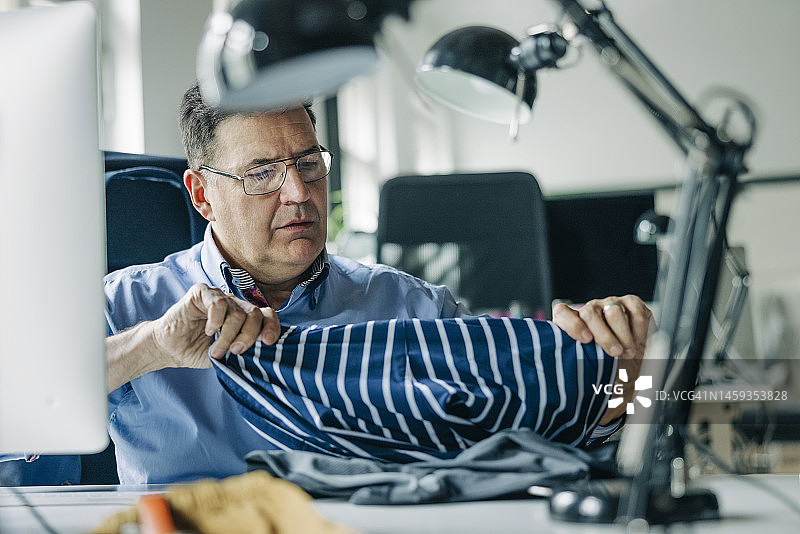 成熟的时装设计师在工作室检查服装的面料质量图片素材