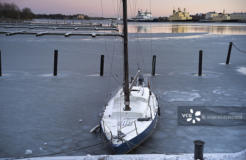 停靠在赫尔辛基港冰冻码头上的孤舟图片素材