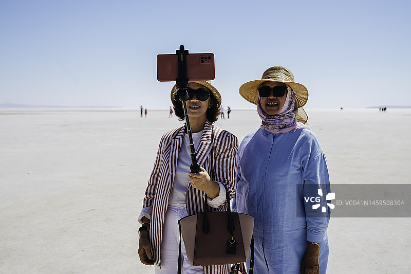 年长的游客在盐湖的白色盐上自拍图片素材