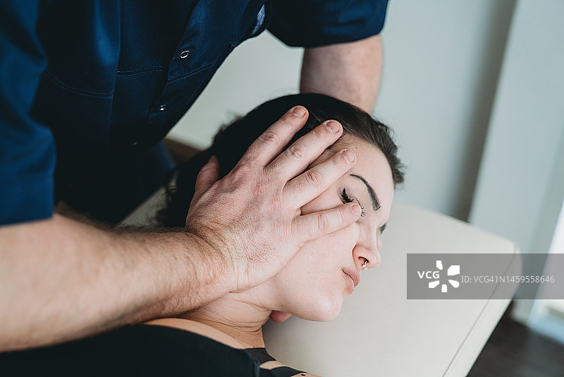 理疗师为年轻女性患者进行脊椎按摩图片素材