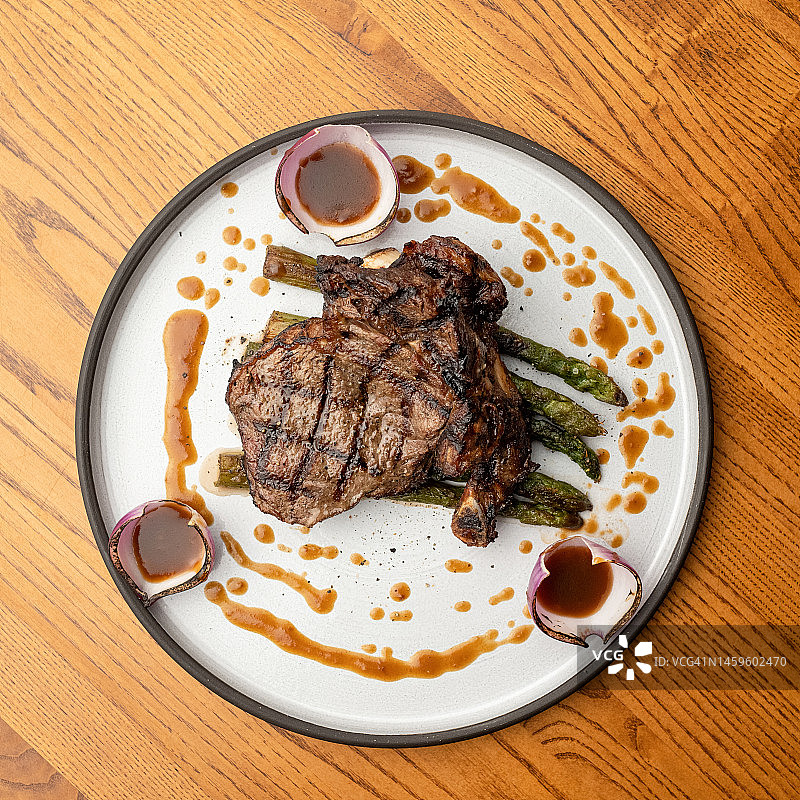 白盘盛装烤T骨牛排配芦笋和酱汁（顶视图）图片素材