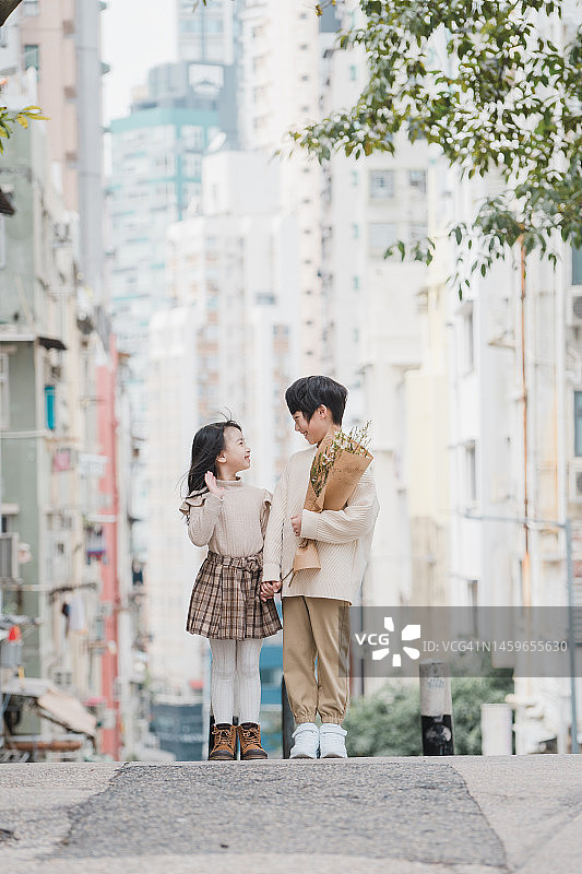 在街上放松的快乐青少年兄妹，拿着鲜花图片素材