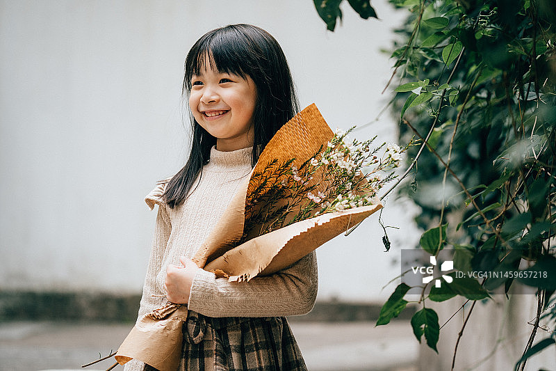 年轻快乐的十几岁女孩亚洲儿童儿童时尚模特站在户外的街道上捧着花束图片素材