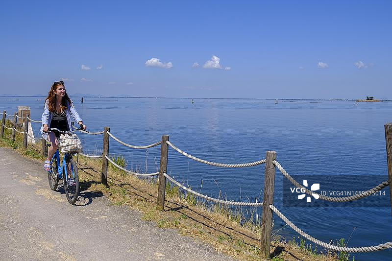 在意大利威尼托基奥贾附近的佩莱斯特里纳岛上骑自行车的骑行者图片素材