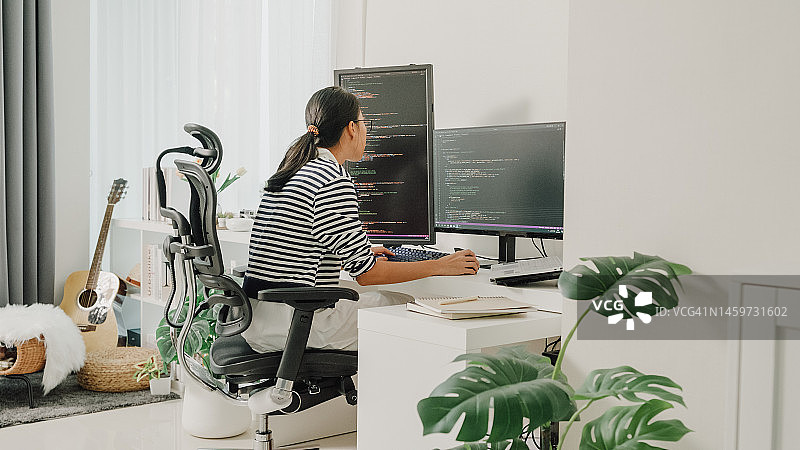 年轻亚洲女性软件开发人员在家远程工作，用电脑编写代码图片素材
