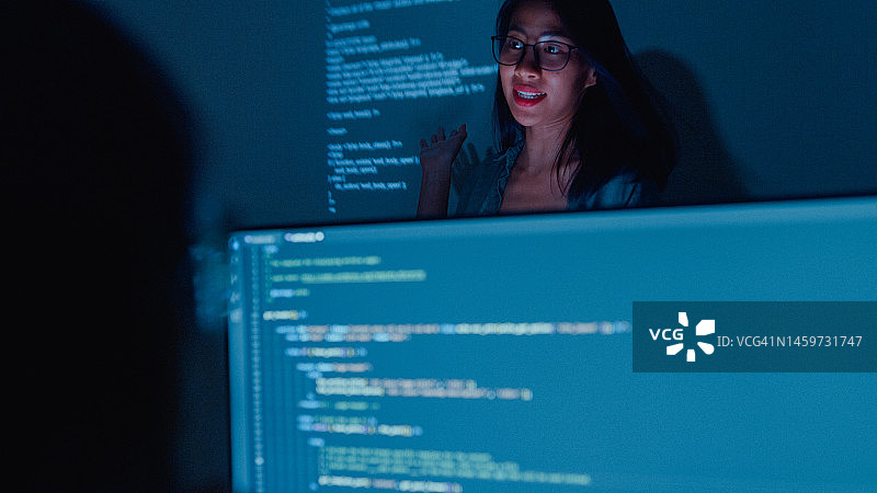 年轻的亚洲女软件开发人员指导团队，与高管团队交谈，分析办公室夜间的源代码图片素材