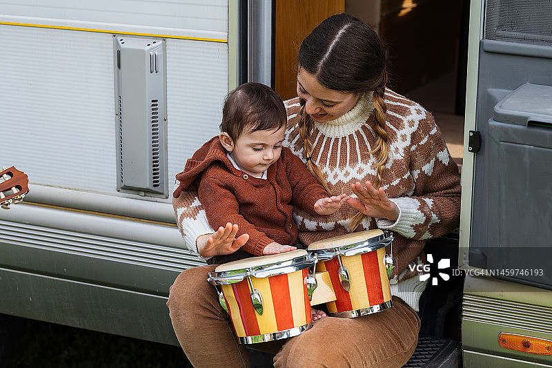 可爱的孩子和他的母亲在面包车上打鼓图片素材