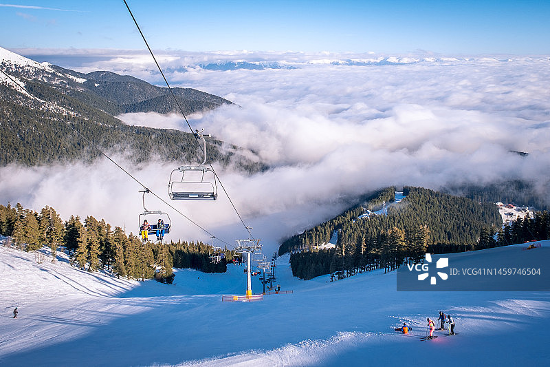 云层之上班斯科全景冬季景观：保加利亚著名滑雪胜地，皮林山脉滑雪坡道景观图片素材