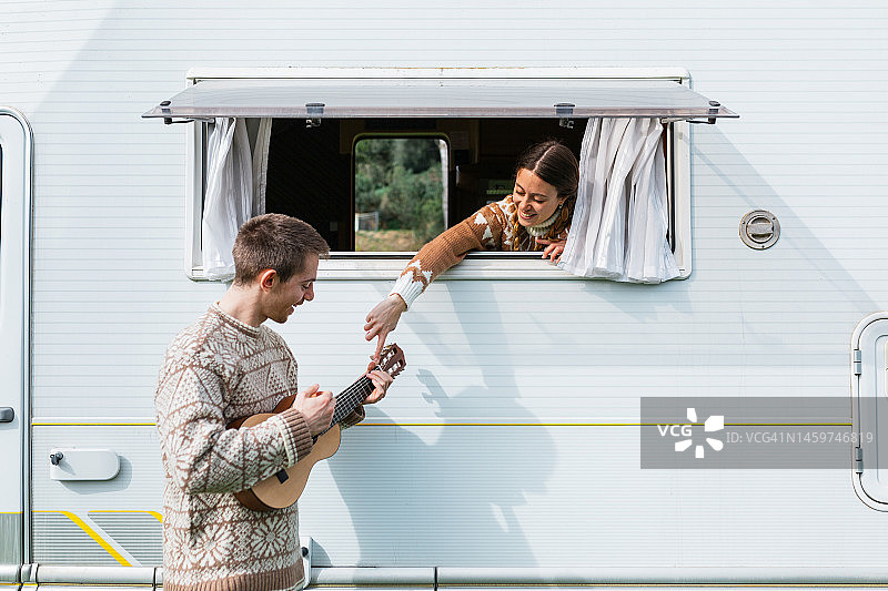 男人在房车旁弹吉他，女子相伴图片素材