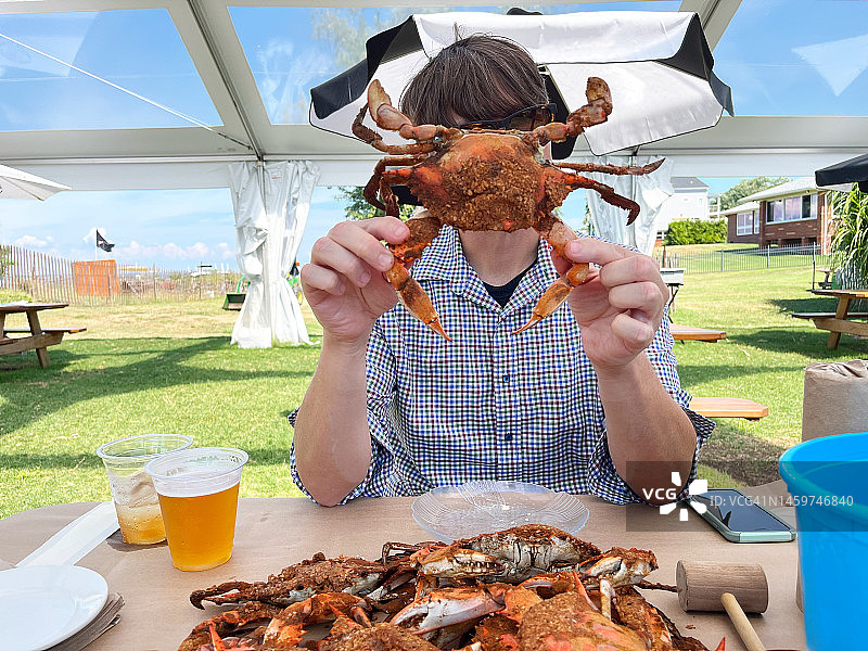 男人吃马里兰蟹，手持香料蟹图片素材