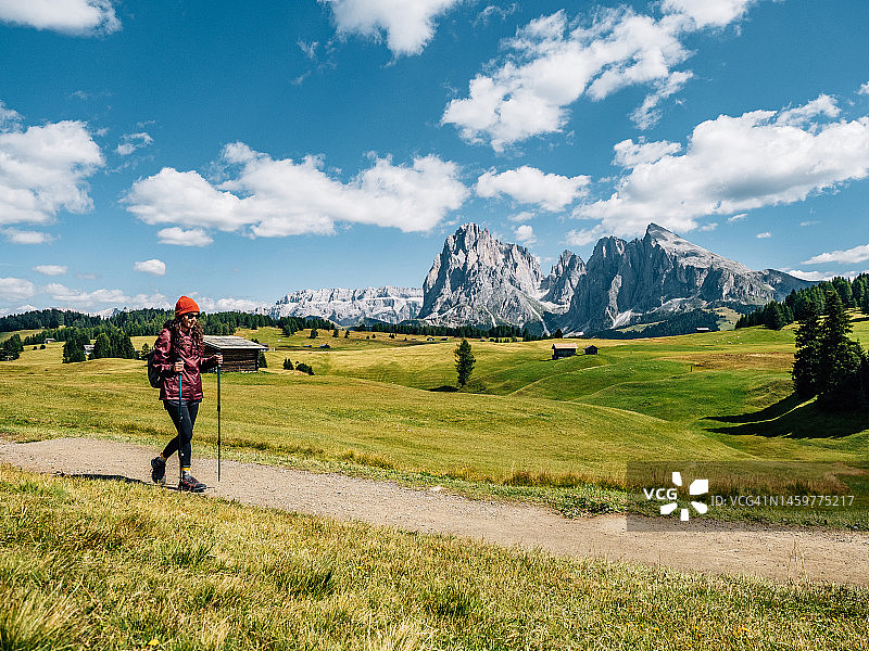 一名妇女在塞伊塞尔阿尔姆步道上拄着登山杖行走图片素材