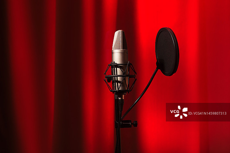 红色霓虹灯背景录音室中的麦克风电容带隔音罩图片素材