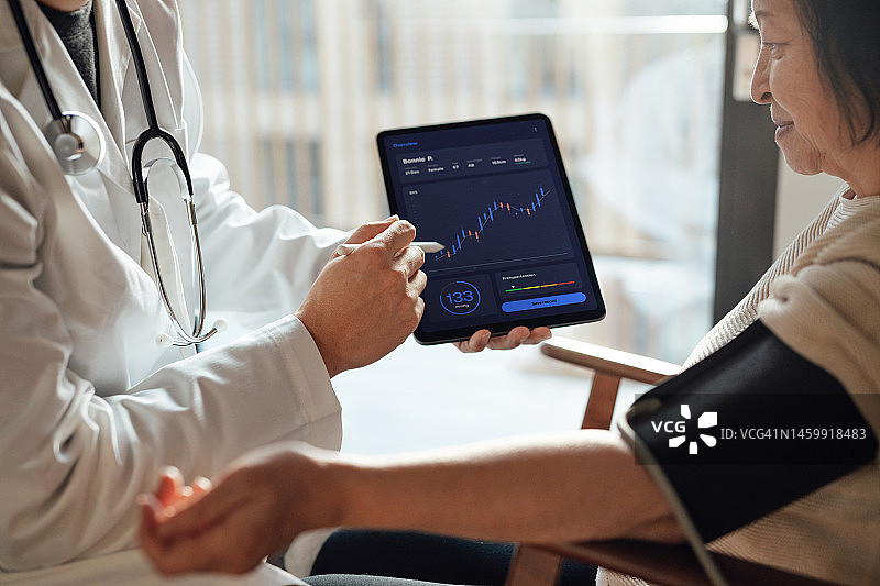 医生用平板电脑向年长的女病人讲解医疗报告图片素材