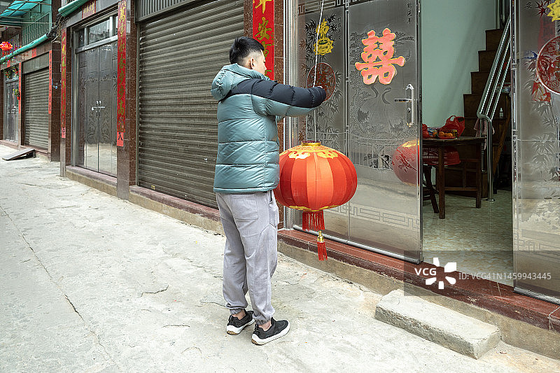 青年正在挂灯笼图片素材
