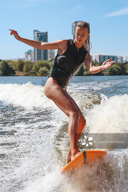 年轻女子在船后进行尾波冲浪训练图片素材