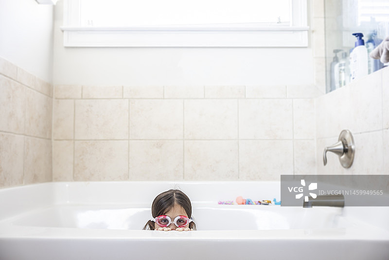 小女孩在浴缸里玩泳镜图片素材