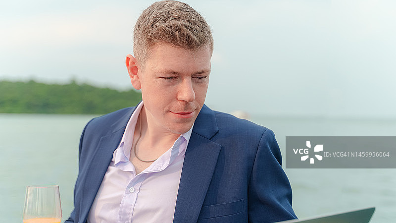 在游艇甲板上使用笔记本电脑的商务男士图片素材