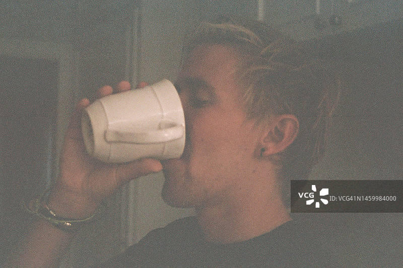 一个年轻人啜饮着杯子里的咖啡图片素材