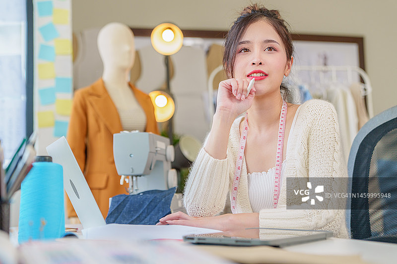 美丽的亚洲时装设计师在电脑笔记本上为新系列绘制草图。设计师创意工作室。图片素材