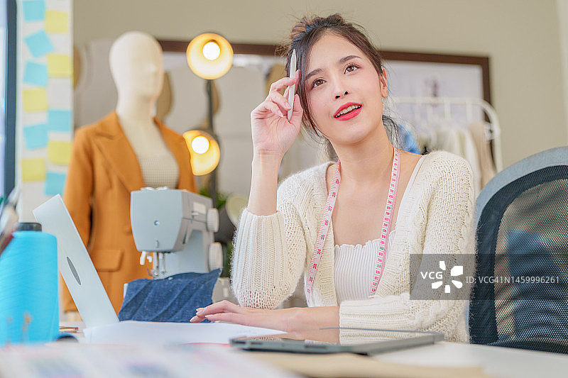 美丽的亚洲时装设计师在电脑笔记本上为新系列绘制草图。设计师创意工作室。图片素材