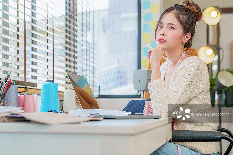 美丽的亚洲时装设计师在电脑笔记本上为新系列绘制草图。设计师创意工作室。图片素材