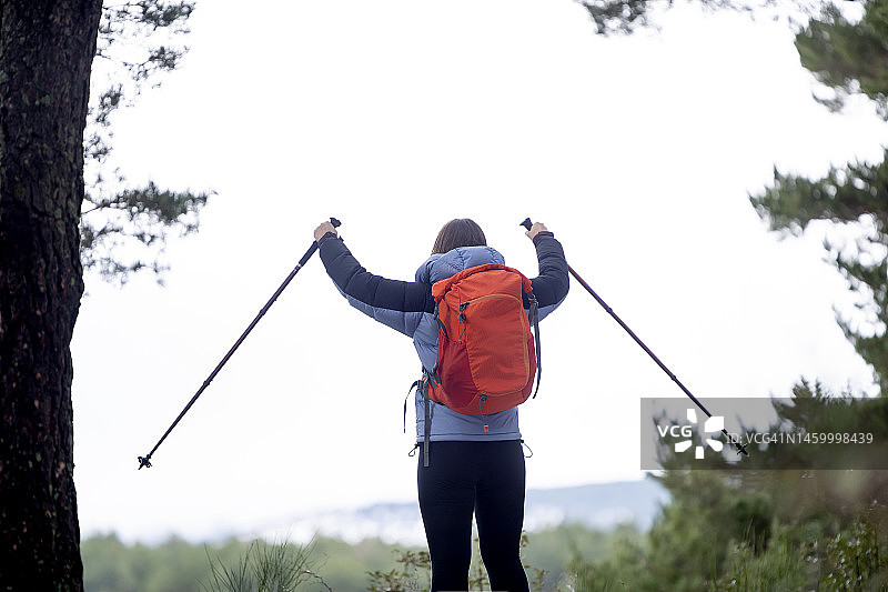 背着背包，拄着登山杖在山中行走的女人图片素材
