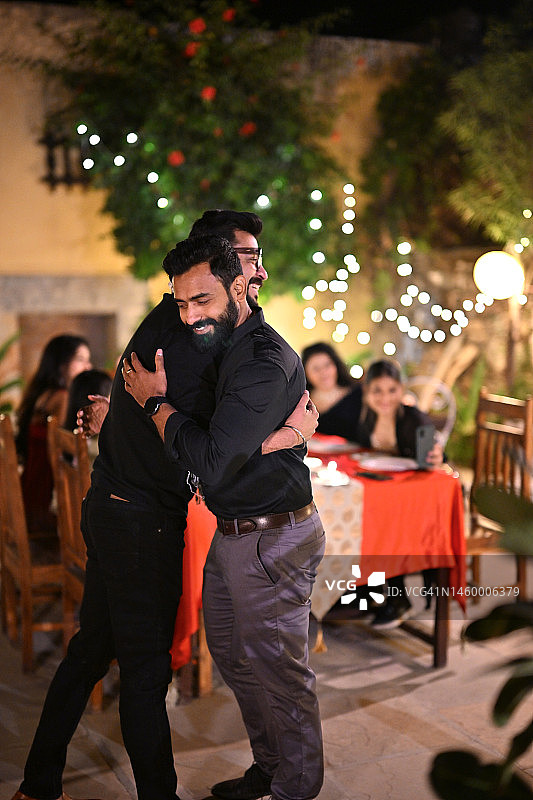 快乐的中年男子在户外晚宴上问候朋友图片素材