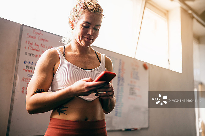 在健身房使用手机的白人女性图片素材
