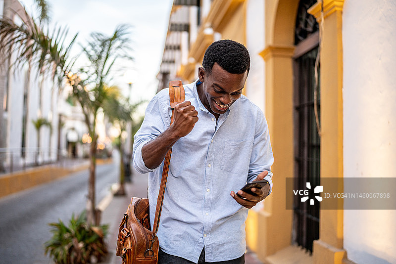 在户外使用手机庆祝的年轻男人图片素材