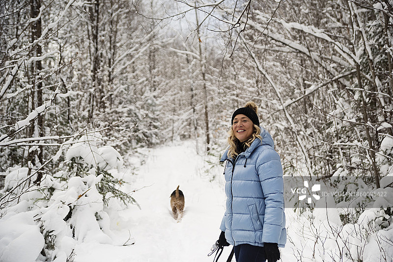 中年妇女在冬日雪地里遛狗图片素材
