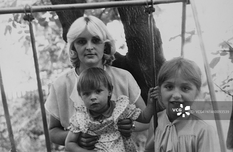 复古家庭照片：在秋千上的女人和两个小女孩图片素材