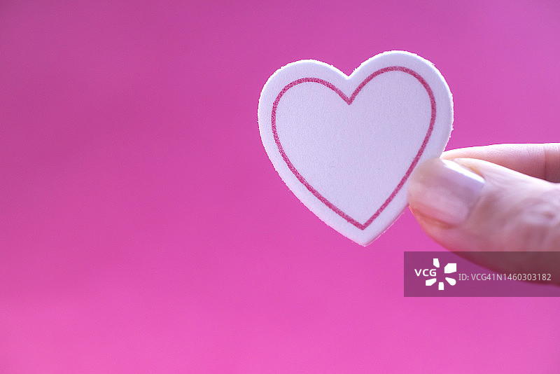 女人手指在粉色背景上做出心形图片素材