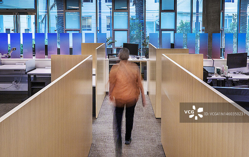 一位女士走在节能绿色办公楼的室内走廊上，旁边是高性能三层镀膜玻璃窗图片素材