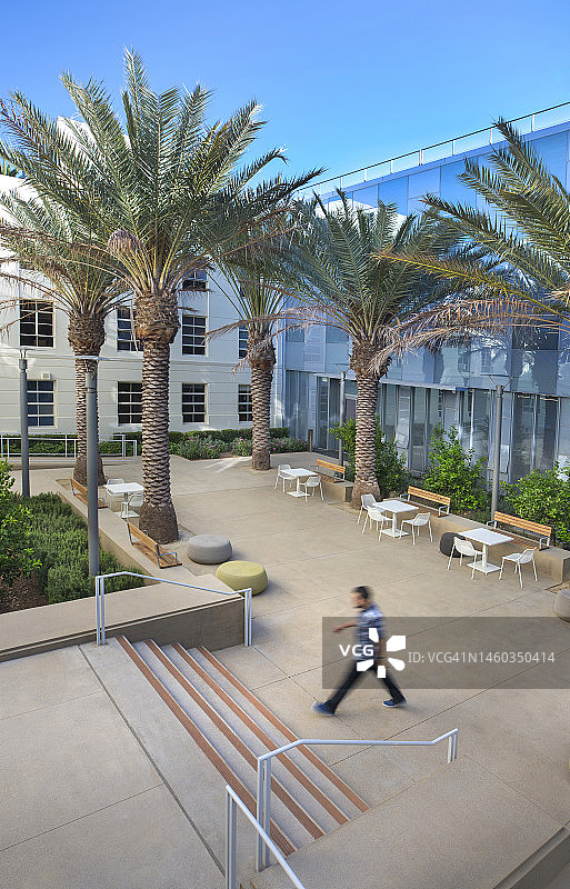 年轻人穿着休闲装走在绿色节能建筑的花园庭院里图片素材