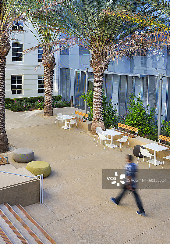 年轻人穿着休闲装走在绿色节能建筑的花园庭院里图片素材