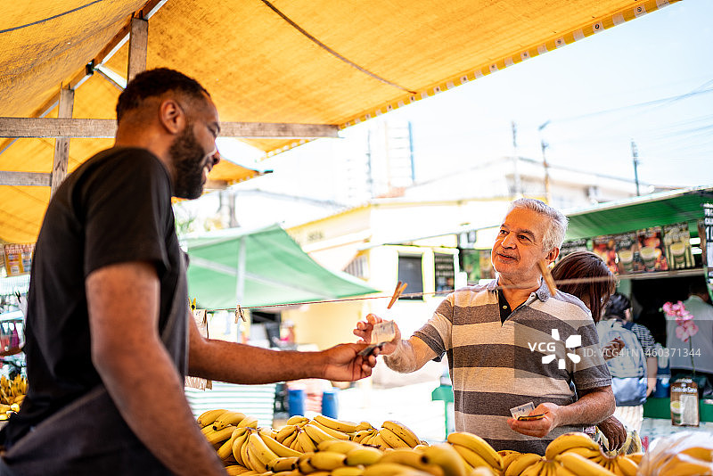 顾客在街头市场向售货员付款购买水果图片素材