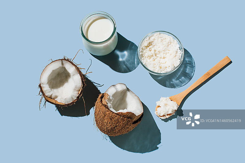 成熟椰子、玻璃杯中的有机纯素椰奶和蓝色背景下的椰子油图片素材