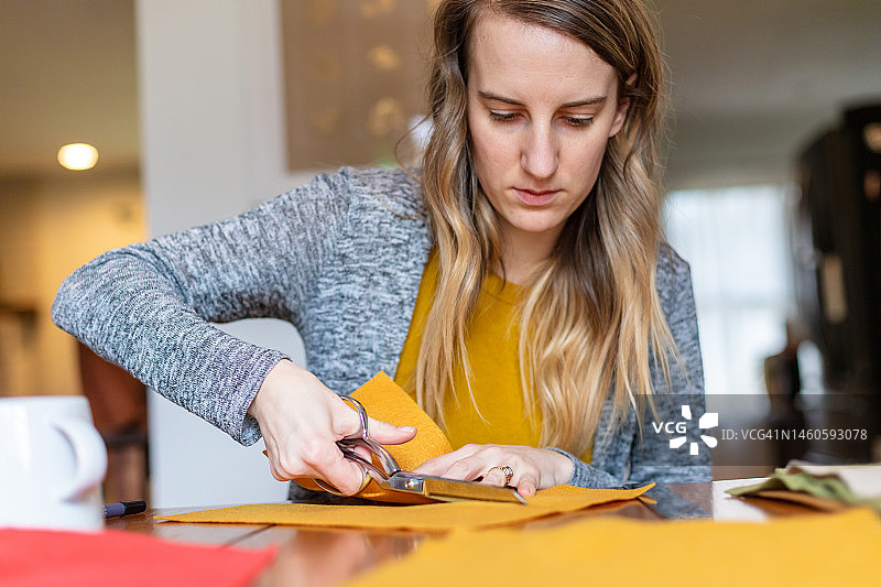 千禧一代的年轻女性在家进行缝纫项目图片素材