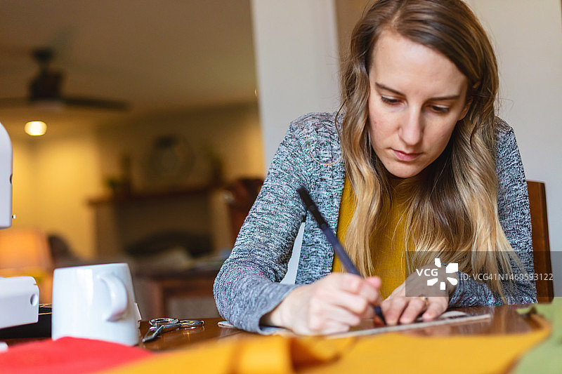 千禧一代的年轻女性在家进行缝纫项目图片素材