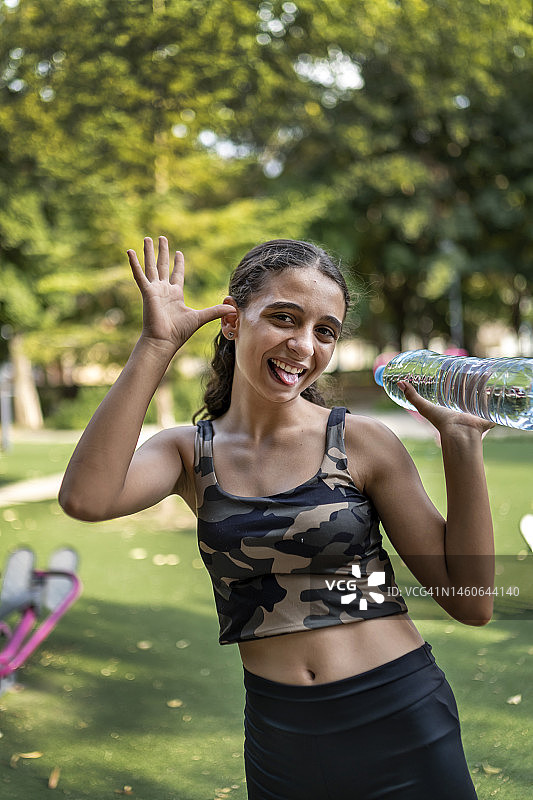 在公园里拿着一瓶矿泉水的运动型青少年女孩图片素材