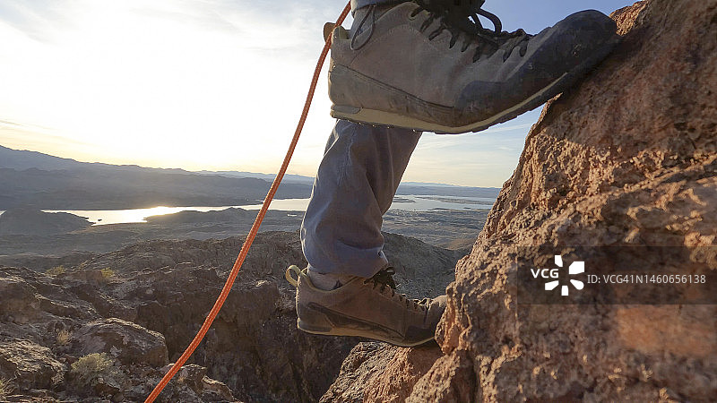 日出时分攀岩者的脚攀登岩壁图片素材