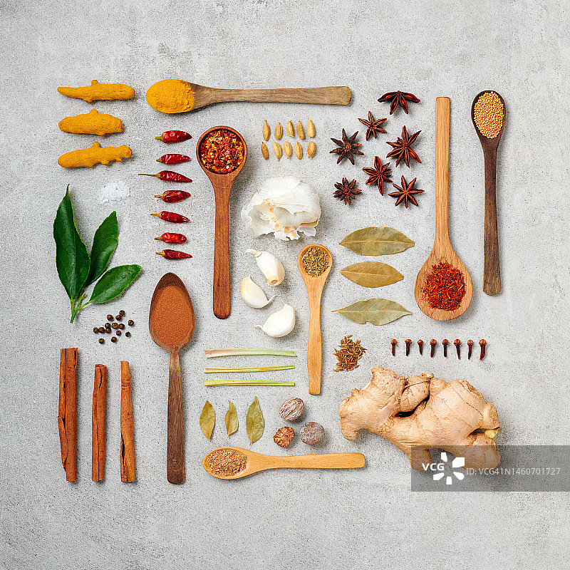 以各种香草、香料和木勺为特色的美食摆拍，背景为混凝土图片素材