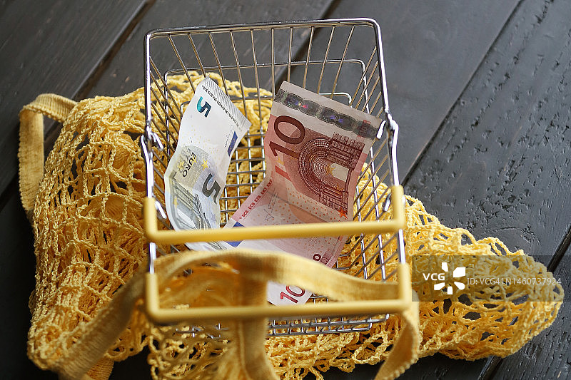 黄色可重复使用购物袋和空购物车，内有欧元纸币图片素材