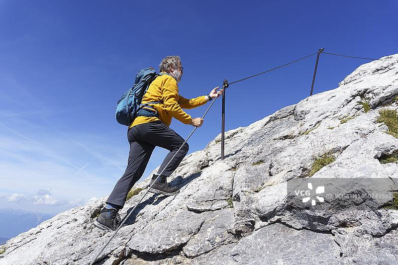徒步旅行者在德国上巴伐利亚韦尔登费尔瑟地区米滕瓦尔德的韦斯特利希卡文德尔峰上使用绳索保险攀登图片素材