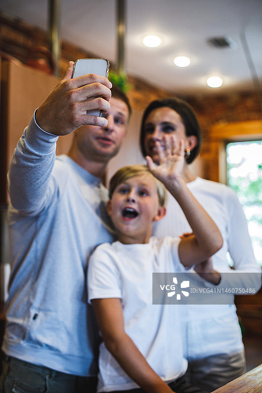 快乐的男孩和他的父母一起在厨房自拍图片素材