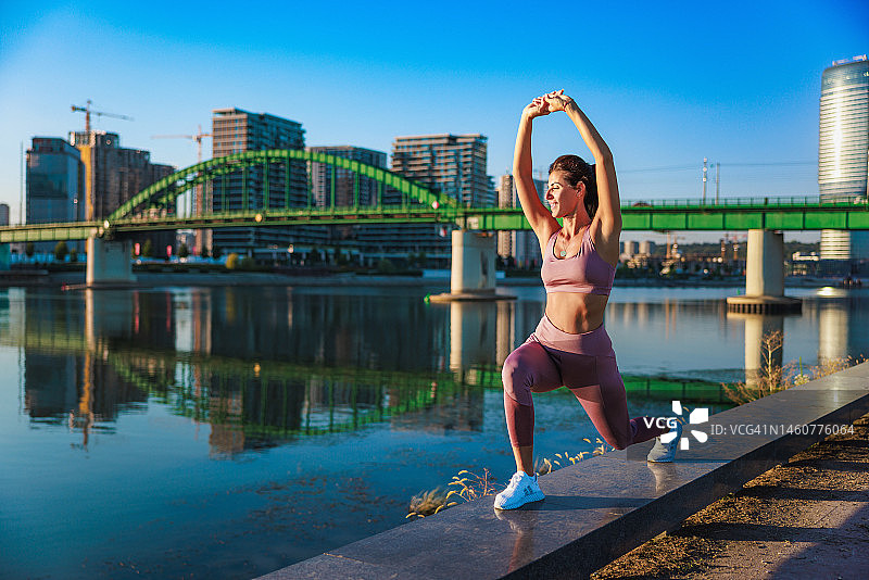 女人弓步拉伸，城市河边平台晴天图片素材