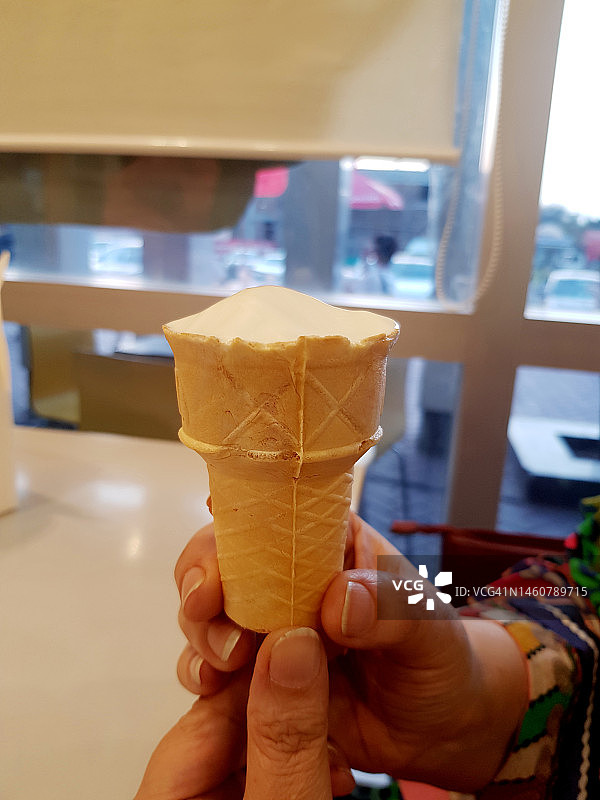 一位女士拿着一个吃过的甜筒冰淇淋图片素材