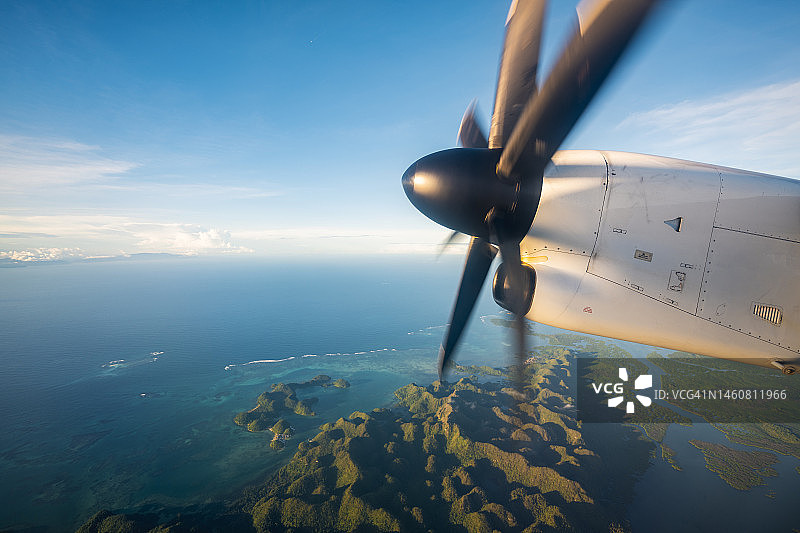 螺旋桨飞机飞越热带岛屿图片素材