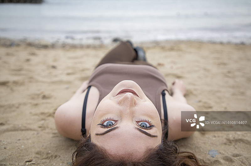 在海滩上伸展身体的蓝眼睛女人图片素材