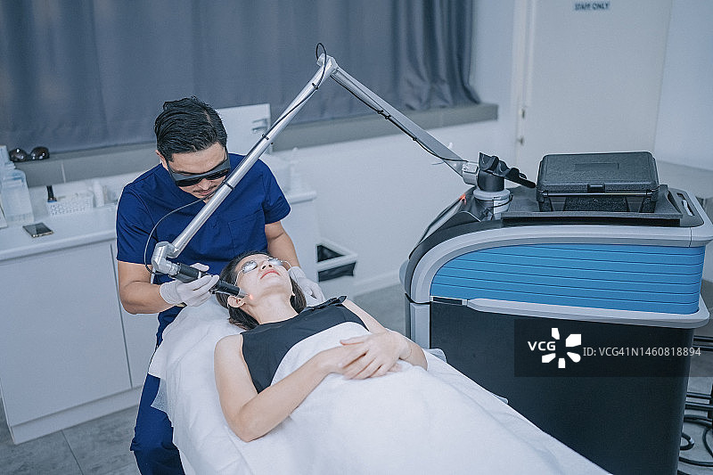 中国男美容师在诊所为女顾客进行激光IPL治疗图片素材